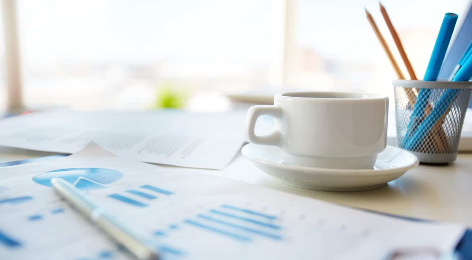 white mug with blue pencils in a cup on a desk